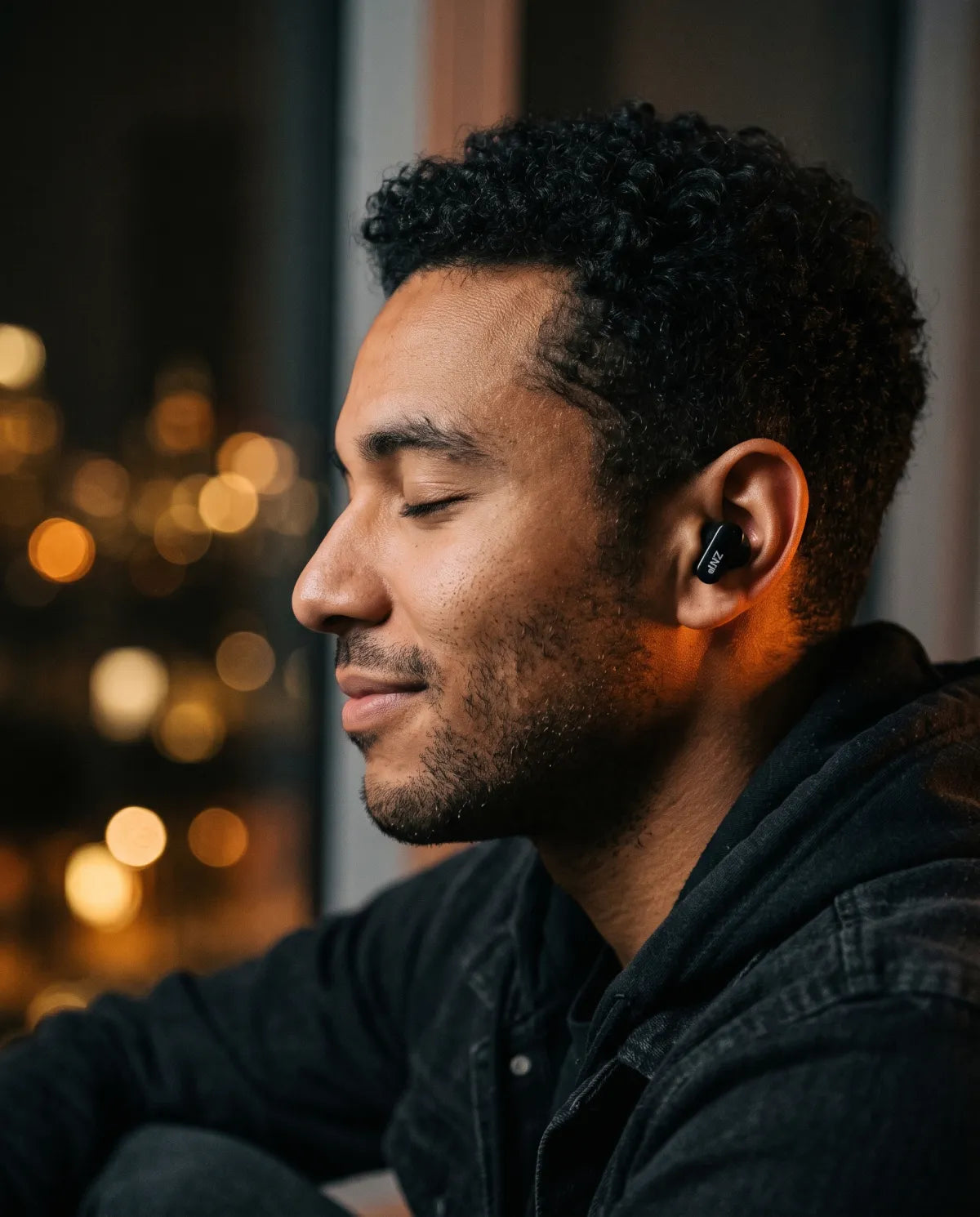 Les yeux fermés, un homme écoute de la musique avec un écouteur ZNP 04, le soir en ville